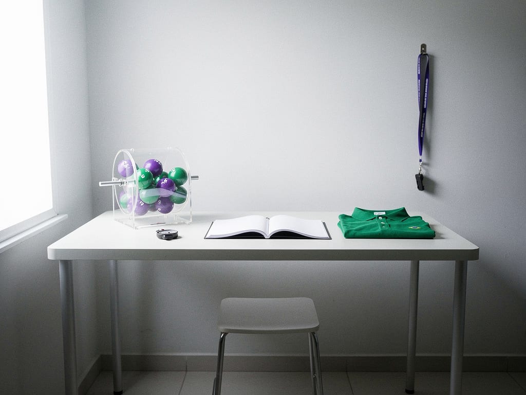 An empty, tidy lottery-shop counter after closing, with a notebook and a ball drum laid out for a planning session.